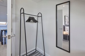 A room with a metal drying rack, a mirror on the wall, and a door leading to another room. - Grace’s Loft - Central Scarborough 1 Bed Apartment (Scarborough)