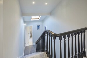 Un escalier surmonté d’une lucarne, une porte en bas et deux tableaux encadrés accrochés au mur.