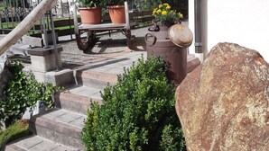 A stone staircase leading to a wooden deck with potted plants and a bench. - Althaus 1 by Interhome (Neukirchen am Großvenediger)