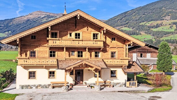 A large wooden chalet with multiple balconies, a stone foundation, and a view of a mountainous landscape. - Althaus 1 by Interhome (Neukirchen am Großvenediger)