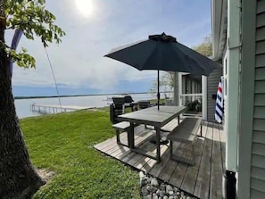 Een terras met een tafel en parasol, uitkijkend op een waterpartij.