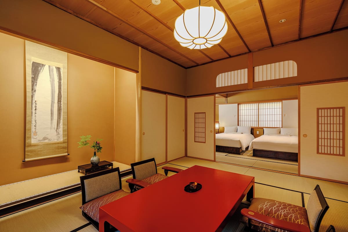 A traditional Japanese-style room with tatami flooring, a low table, and a bed with futon mattresses.