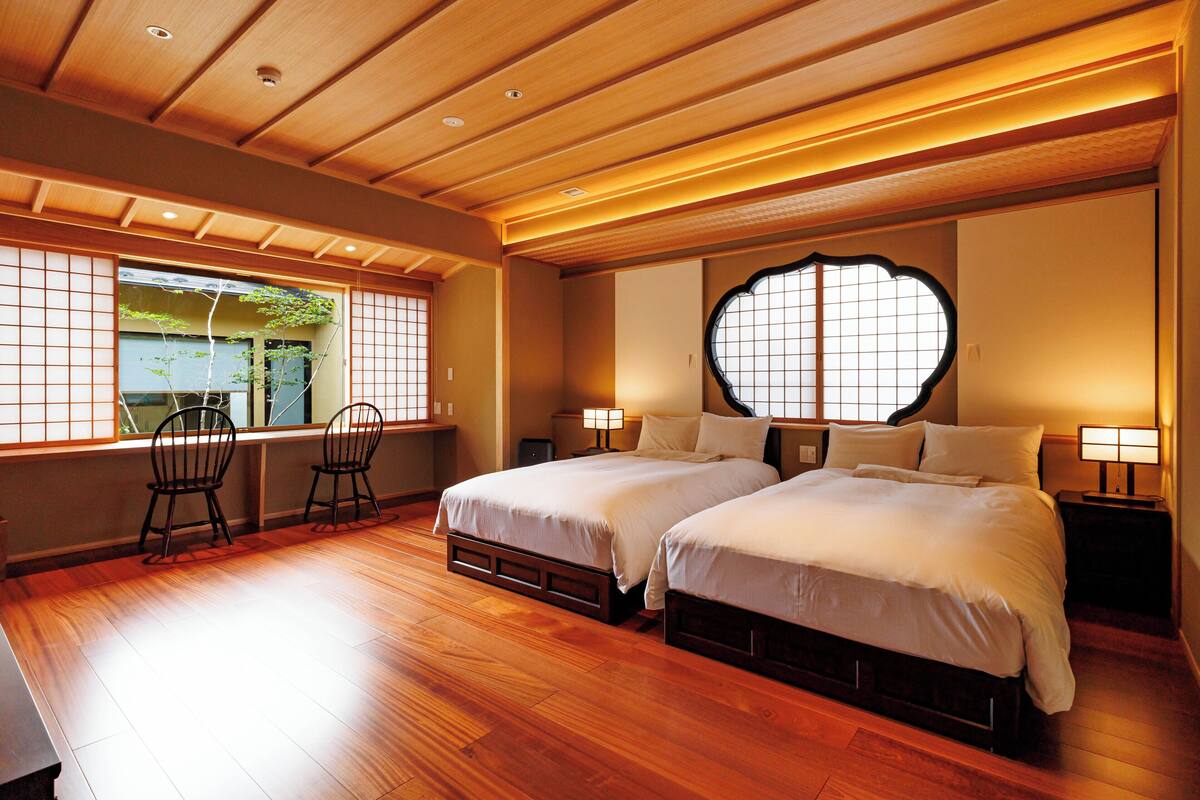 A traditional Japanese-style bedroom with two beds, wooden flooring, and sliding doors.