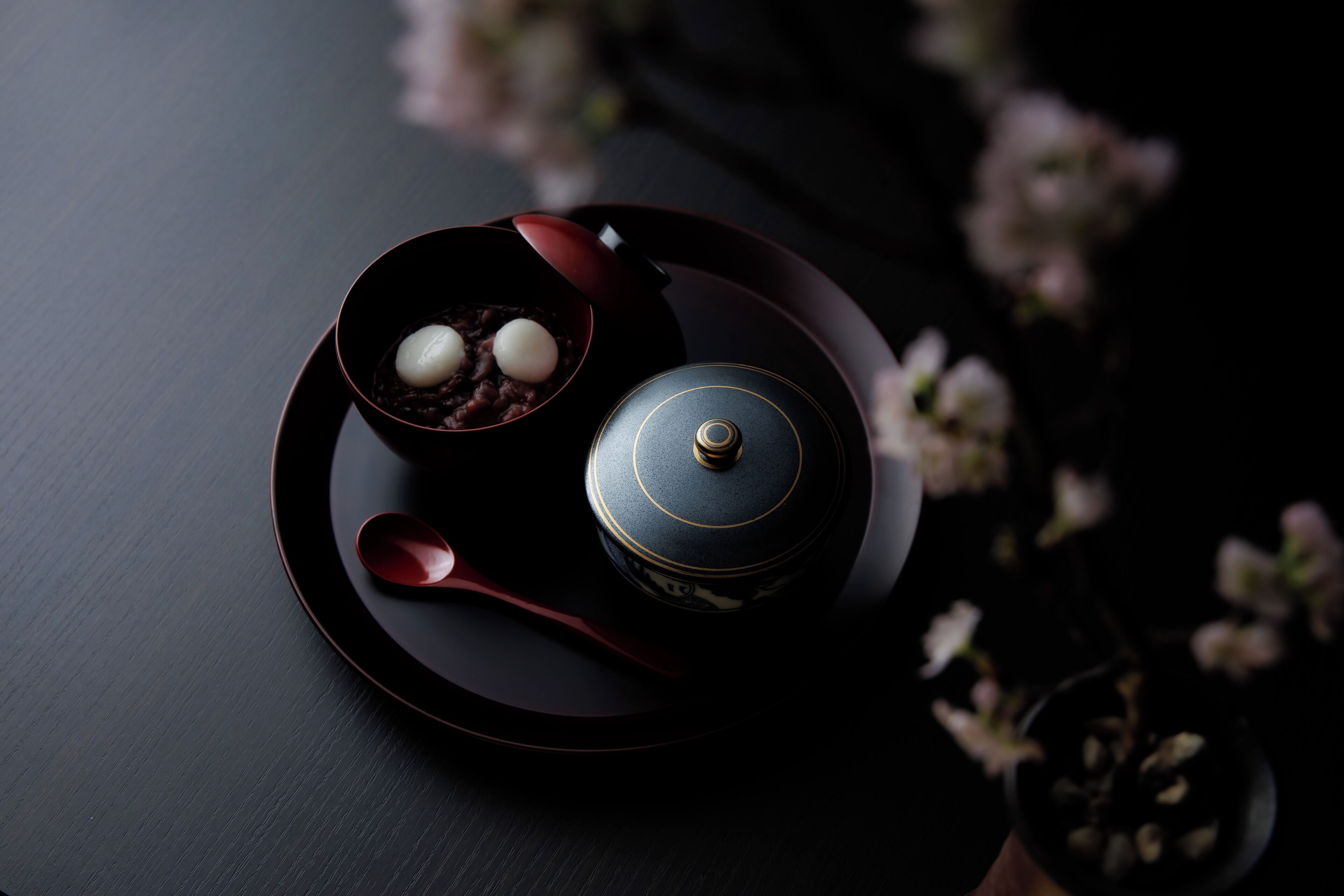 A dark wooden table with a teapot, teacup, and spoon.