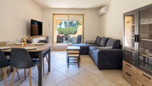 Un espacio habitable compacto con comedor, sofá, televisor y vitrina de vidrio.