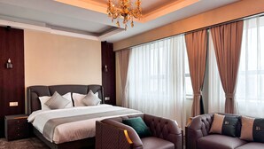 Ein modernes Hotelzimmer mit einem großen Bett, zwei Sofas, einem Glastisch und einer Kristallleuchtre.