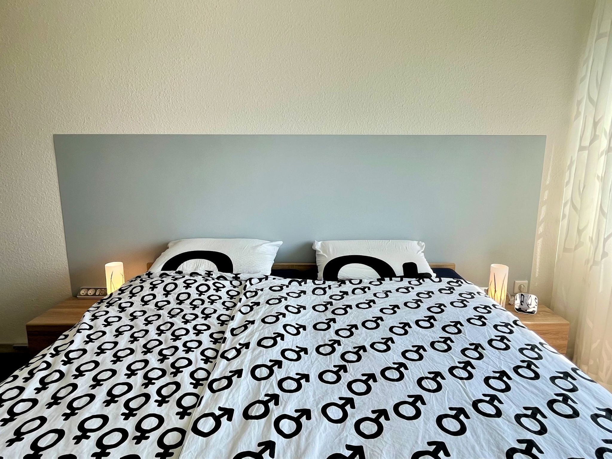A bed with a patterned bedspread, two pillows, and bedside lamps.