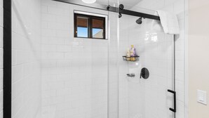A glass-enclosed shower with white tiles, a window, and a towel rack. - 2BR condo in West Yellowstone, just 1 minute from the park! Owl's Nest (West Yellowstone)