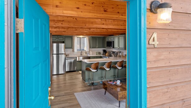 A modern kitchen with stainless steel appliances, a bar area with stools, and a wooden ceiling. - 2BR condo in West Yellowstone, just 1 minute from the park! Owl's Nest (West Yellowstone)