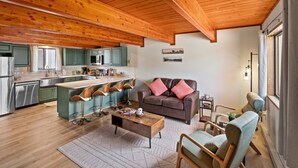 A spacious living area with a wooden ceiling, a brown sofa with red cushions, and a dining area with green cabinets and a wooden coffee table. - 2BR condo in West Yellowstone, just 1 minute from the park! Owl's Nest (West Yellowstone)