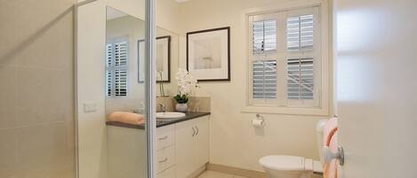 Een moderne badkamer met een douchecabine van glas, een wit toilet en een wastafel met aanrechtblad.