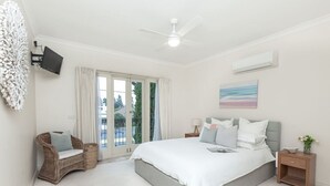 A bedroom with a large bed, a television, a ceiling fan, and a window with curtains. - `Beach Side` Warrnambool CBD (Warrnambool)