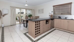 A modern kitchen with a central island, wooden cabinets, and a dining area with chairs. - `Beach Side` Warrnambool CBD (Warrnambool)