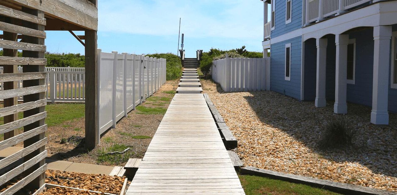 A wooden pathway leading to a building with a balcony.