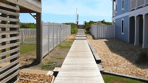 A wooden pathway leading to a building with a balcony. - Shore 'Nuf - 3 BR Oceanside in Duck (Duck)