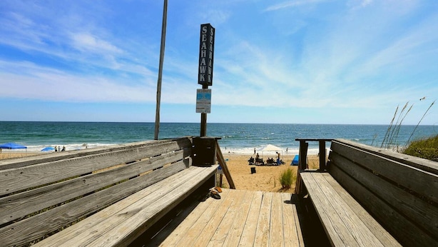 A wooden boardwalk leading to a beach with a signpost and a bench. - Shore 'Nuf - 3 BR Oceanside in Duck (Duck)