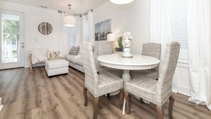 Een eetruimte met rieten stoelen, een ronde witte tafel en een kroonluchter.