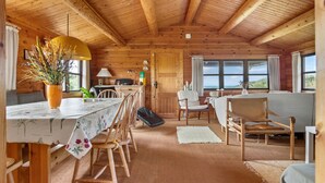 A wooden cabin interior with a dining area, a sofa, and a view of the outdoors. - 2 bedroom lovely home in Saltum (Saltum)