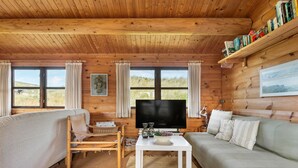 A cozy cabin interior with a wooden ceiling, a television, a sofa, a chair, and a bookshelf. - 2 bedroom lovely home in Saltum (Saltum)