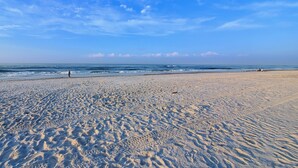 Une vaste plage de sable fin, avec des vagues douces et un ciel dégagé.