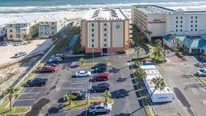 Un hôtel doté d’un parking, offrant une vue sur la plage, et composé d’un grand bâtiment sur lequel est apposée une enseigne.