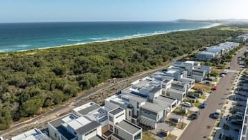 A coastal residential area with modern buildings, a road, and a beach.