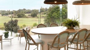 A dining area with wicker chairs and a round table, overlooking a scenic landscape. - Oceanfront Oasis | Stylish 4BR w/ Epic Terrace (Magenta)