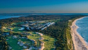 An aerial view of a coastal golf course with sand dunes, a beach, and a residential area. - Oceanfront Oasis | Stylish 4BR w/ Epic Terrace (Magenta)