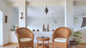 A room with two wicker chairs and a small round table, a potted plant, and decorative items on the wall. - Attara Hills Sunset Villa Senggigi (Senggigi)