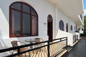 A building with large arched windows, a balcony with wicker chairs, and a small table. - Attara Hills Sunset Villa Senggigi (Senggigi)