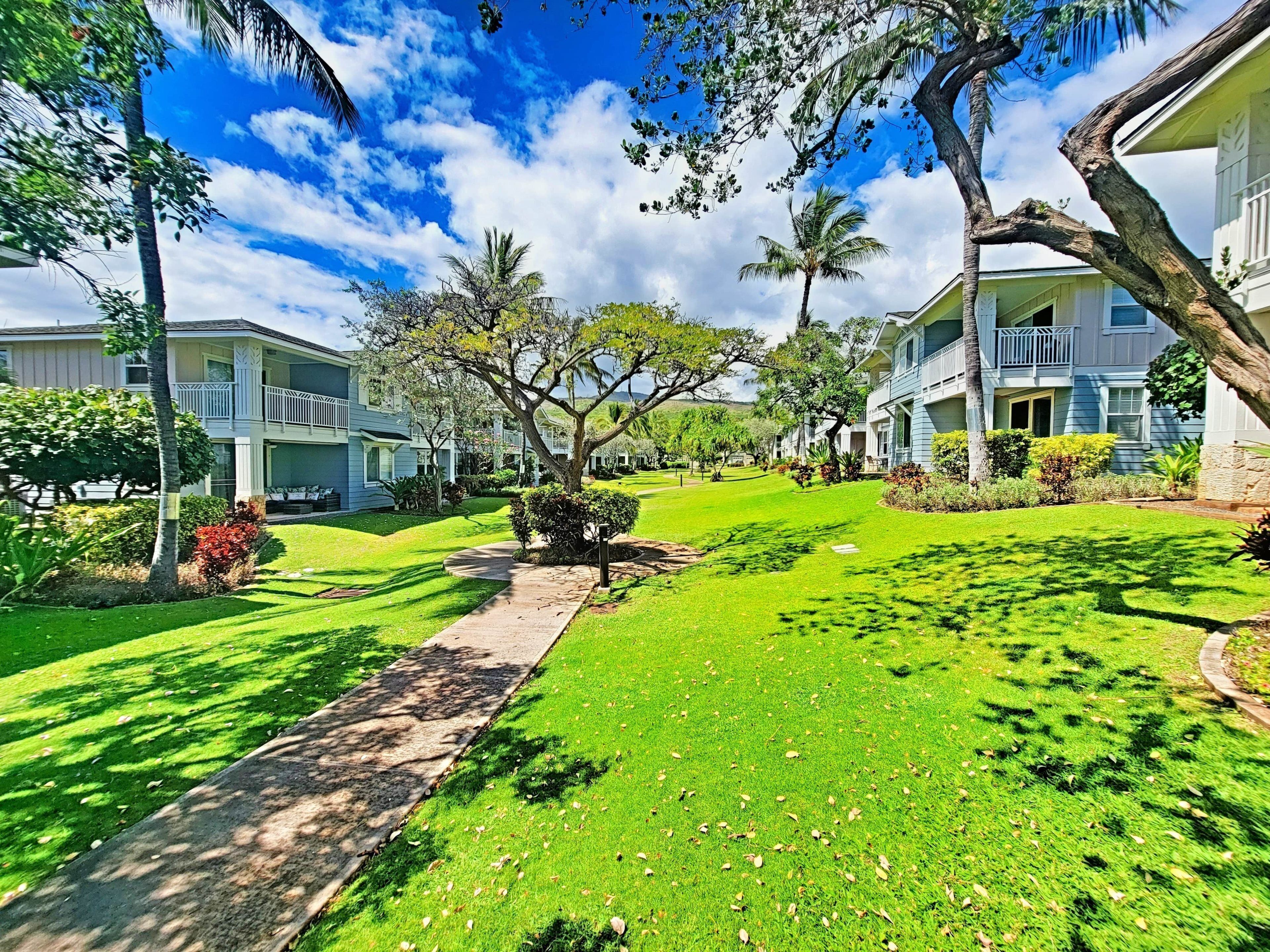 A residential area with multiple two-story houses, a well-maintained lawn, and a clear sky.