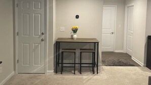 A hallway with a door, a small table with a vase of flowers, and a carpeted floor. - Stylish Decor Studio (Tega Cay)