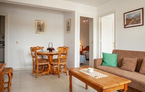 Relax in this open-plan living space with a dining area and seating area, featuring a wooden dining table, coffee table, and comfortable sofa.