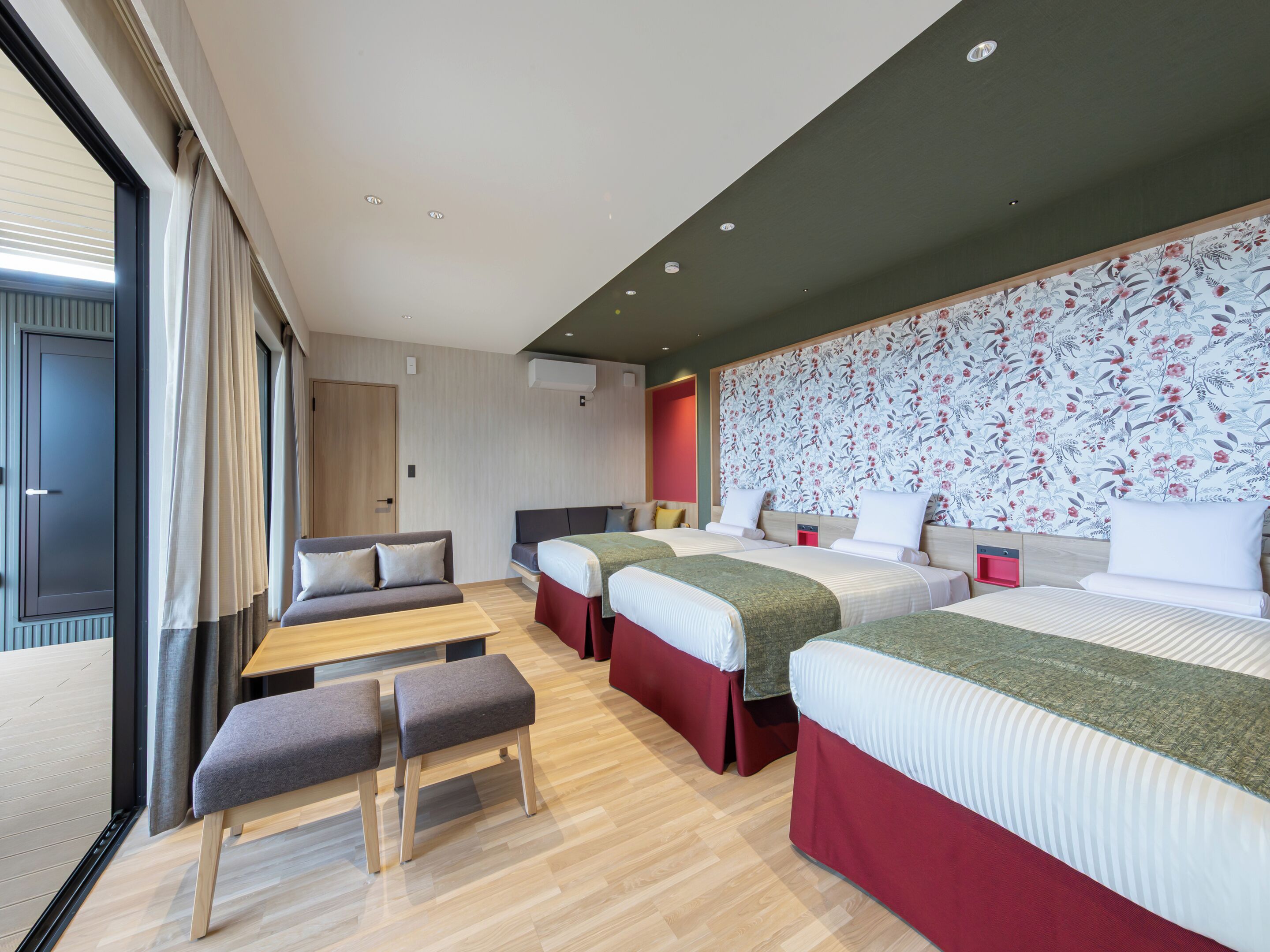 Una habitación de hotel moderna con una cama grande, dos camas más pequeñas, un sofá y un banco.