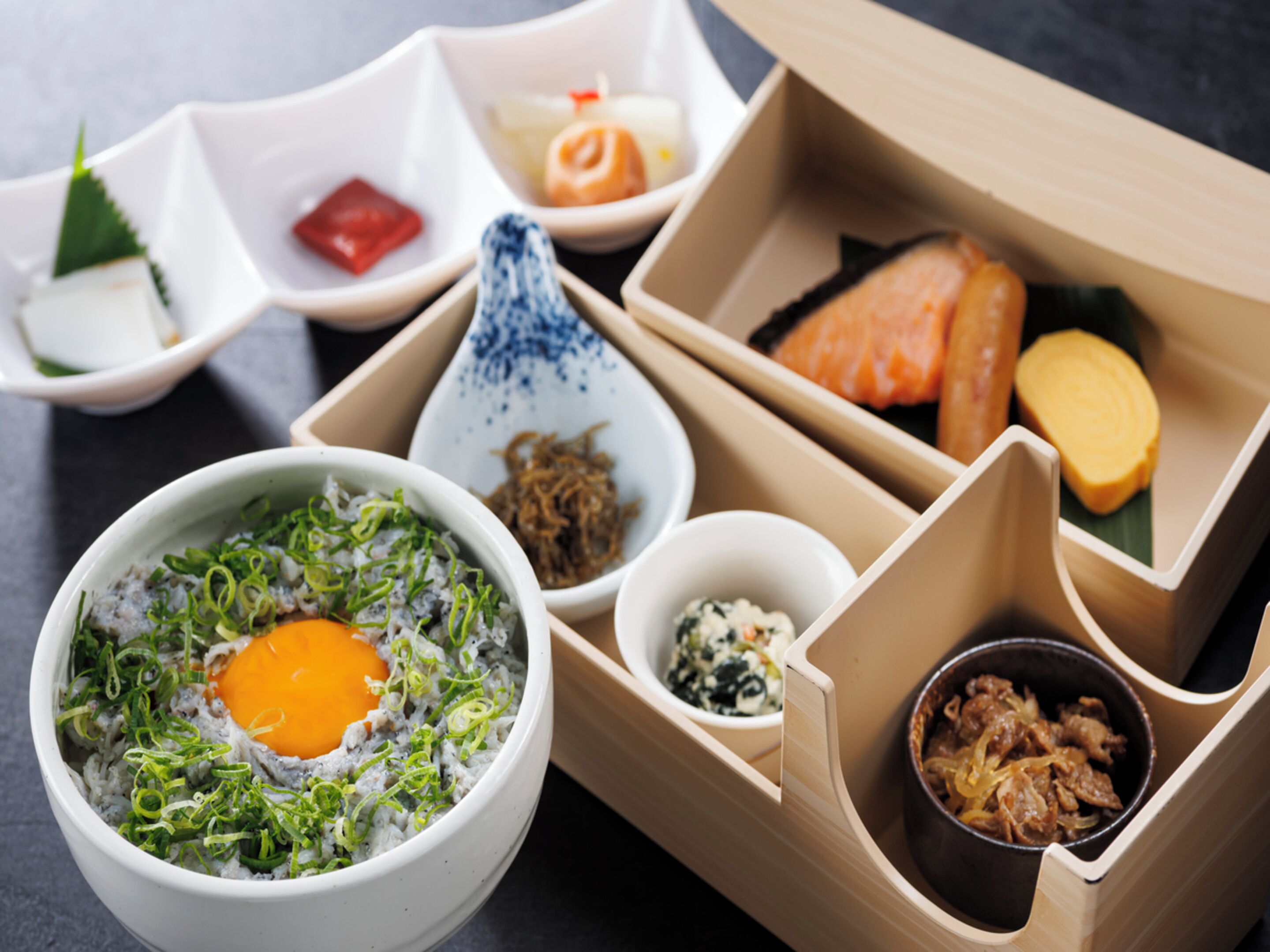 Una comida tradicional japonesa con diversos platos, incluyendo arroz, pescado y verduras encurtidas.