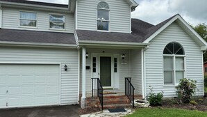 A two-story house with a garage, a front porch with steps, and a brick entryway. - Welborn House - Creekside  (Mountain City)