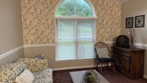 A room with a large window, a sofa, a chair, a small table, and a cabinet. - Welborn House - Creekside  (Mountain City)