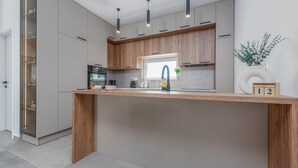 Eine moderne Küche mit Kochinsel, eingebauten Geräten und Pendelleuchten.