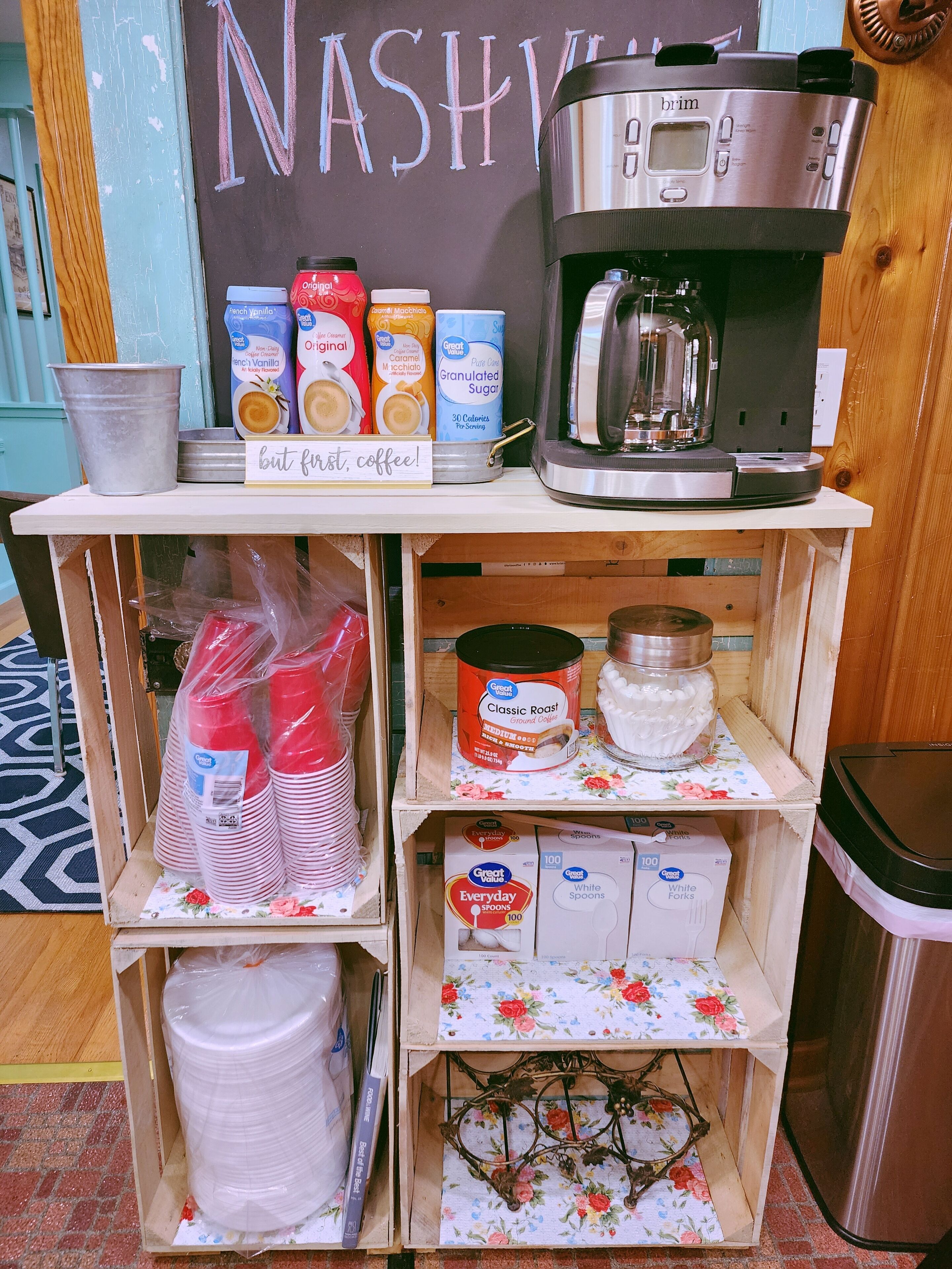 Una estación de café con cafetera, cápsulas de café y un cartel que dice 'pero antes, café'.