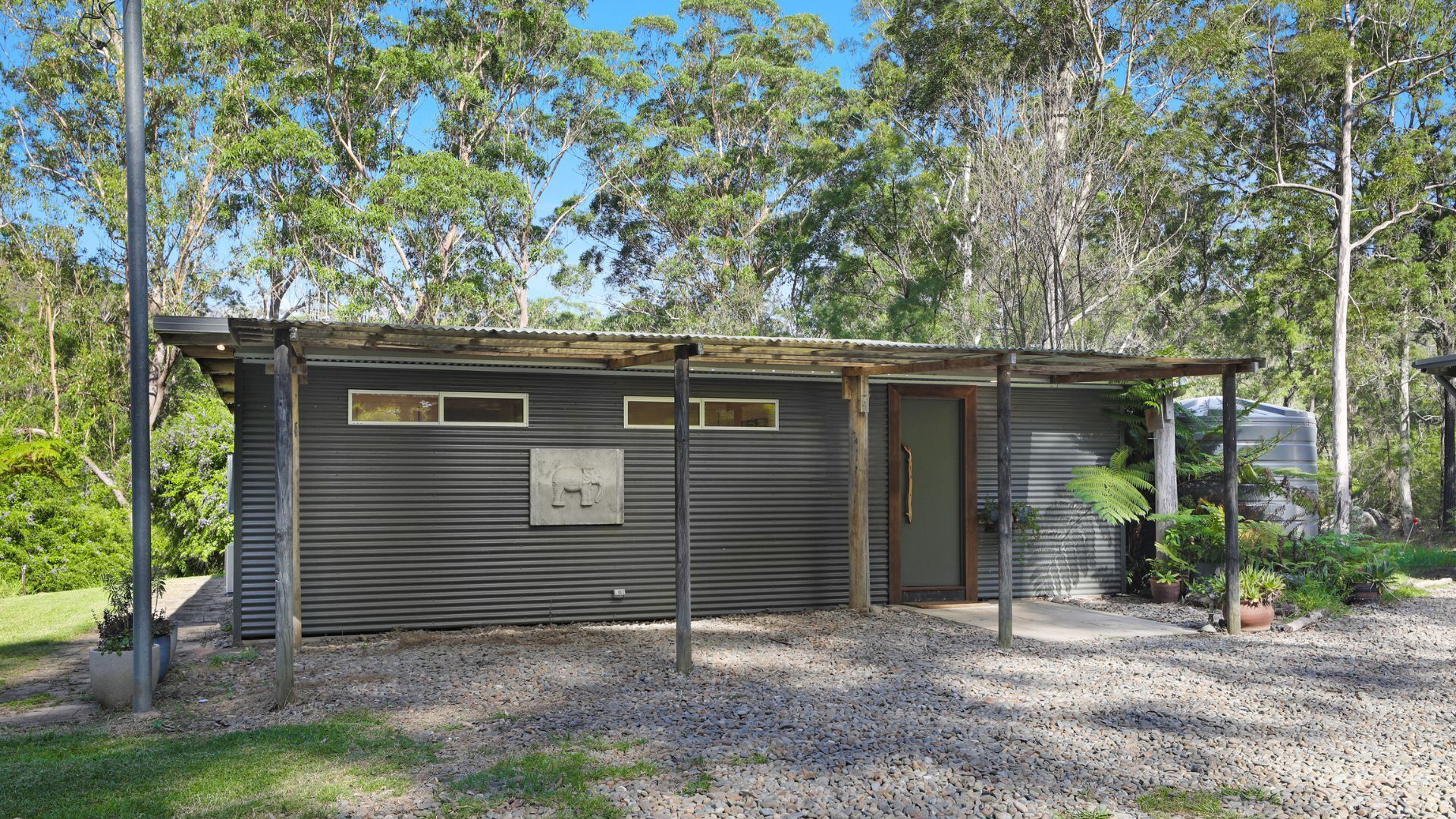 A small, single-story metal building with a corrugated roof, a wooden door, and a window with a metal frame.