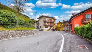 A curved road in a village with stone walls, colorful buildings, and a clear sky. - Awesome apartment in Pezzoro (Pezzoro)