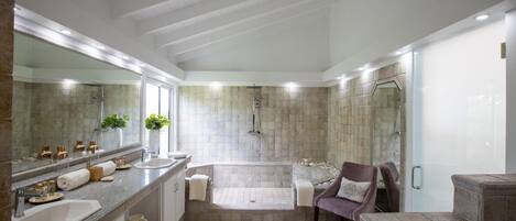 A modern bathroom with a large mirror, two sinks, a bathtub, and a shower.