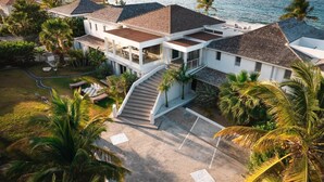 A coastal resort with multiple buildings, a swimming pool, and palm trees.