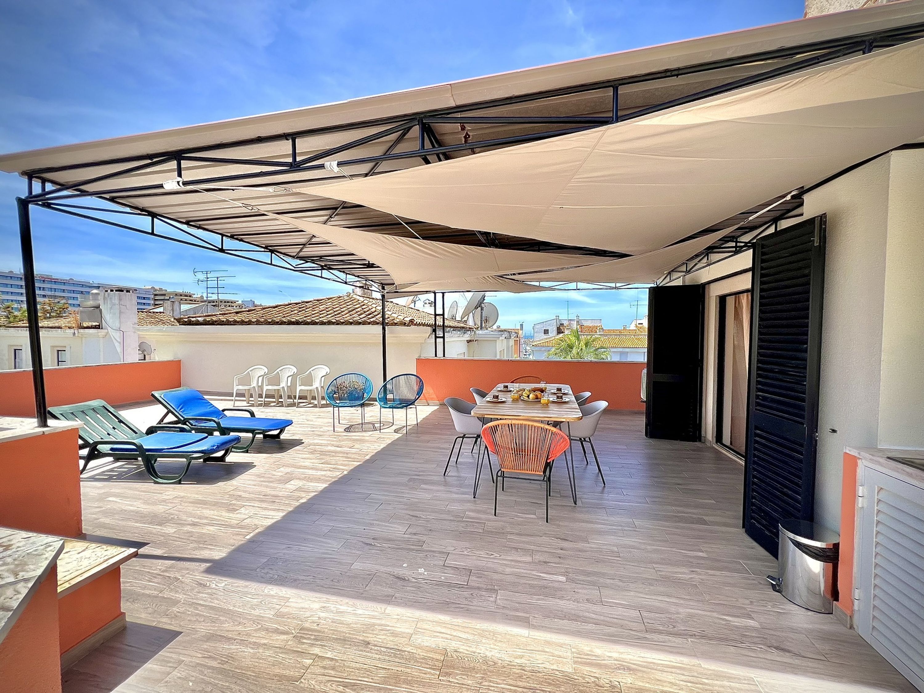 Une terrasse sur le toit dotée d’un espace salon couvert, d’une table de billard et d’une table à manger avec des chaises.