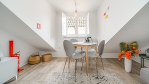 A modern, well-lit dining area with a round table, grey chairs, and a white vase with flowers. - Nomad s Castel Lisbon - 1bdr The Reader (Lisbon)