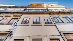 A building facade with multiple windows, a parking sign, and a clear blue sky. - Nomad s Netto Subway - Sunny Balcony (Porto)