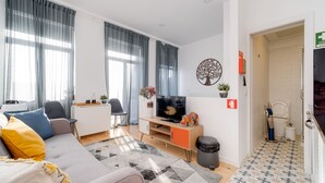 Un salon moderne avec un canapé, un téléviseur et un petit bureau.