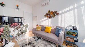 Un salon moderne avec un canapé gris, une table basse, une table d’appoint bleue et un élément décoratif mural.