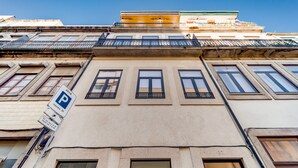 La façade d’un immeuble avec un panneau indiquant un parking, de nombreuses fenêtres et un balcon.