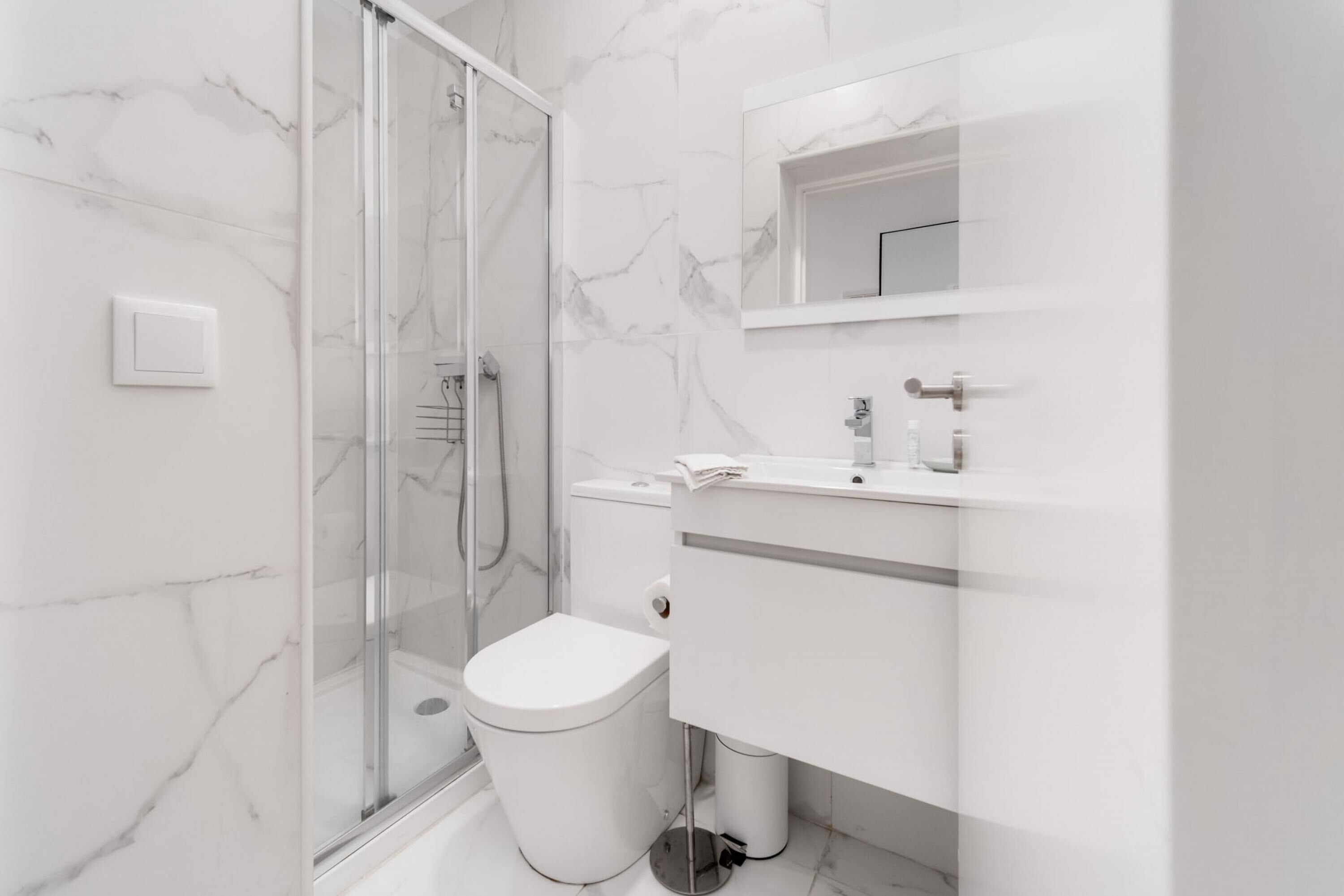 A modern bathroom with a glass shower enclosure, a toilet, and a vanity with a mirror.